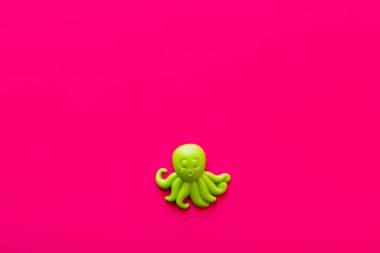 top view of green plastic octopus on pink background clipart
