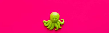 top view of bright green octopus toy on pink background, banner clipart