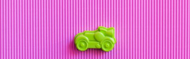 top view of green vintage toy car on violet corrugated background, banner clipart