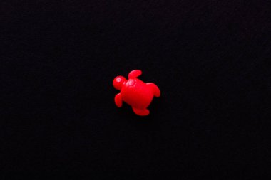 Siyah üzerine izole edilmiş parlak kırmızı plastik kaplumbağanın üst görüntüsü