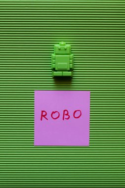 top view of plastic toy near purple paper with robo inscription on green background clipart