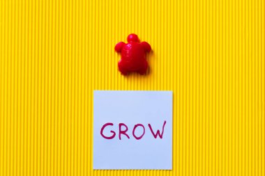 top view of blue card with grow lettering near red toy turtle on yellow background clipart