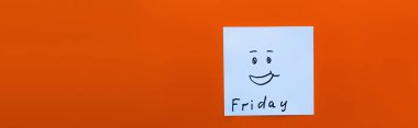 top view of cheerful emoticon near friday lettering on sticky note on red background, banner clipart