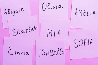 Menekşe arkaplanda farklı kadın isimleri olan yapışkan notların üst görünümü