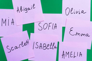 top view of pale purple cards with female names on green background clipart