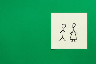 Yeşil arka planda erkek ve kadın simgelerinin olduğu kağıt kartın üst görünümü
