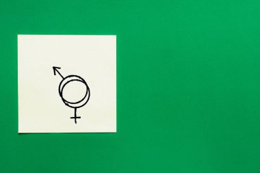 Yeşil arkaplanda birbirine bağlı cinsiyet kimlik işaretlerine sahip kağıt kartının üst görünümü