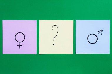 top view of multicolored cards with question mark between gender signs on green background clipart