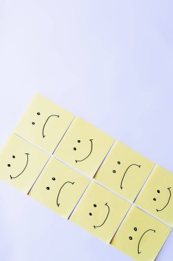 top view of pale yellow sticky notes with happy and upset emoji on white background clipart