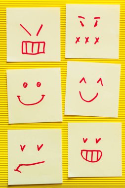 Sarı desenli arka planda neşeli ve kızgın emojili kartların üst görünümü