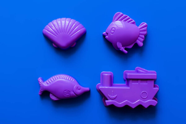 top view of plastic forms in shape of marine animals and ship on blue background