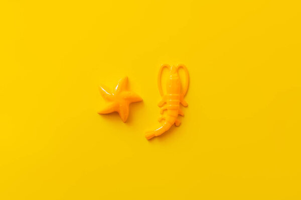 top view of bright plastic shrimp and starfish on yellow background