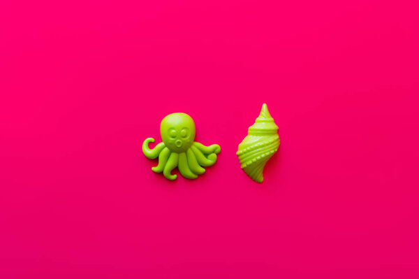 top view of green octopus and shellfish toys on pink background