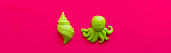 top view of bright green shellfish and octopus toys on pink background, banner