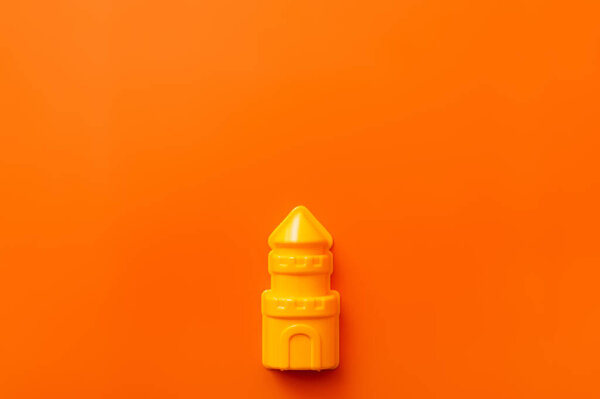 top view of bright yellow plastic tower on orange background