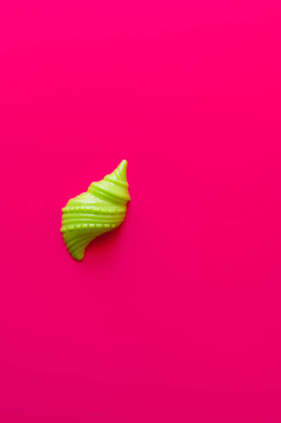 top view of green sand mold in shape of shellfish on pink background