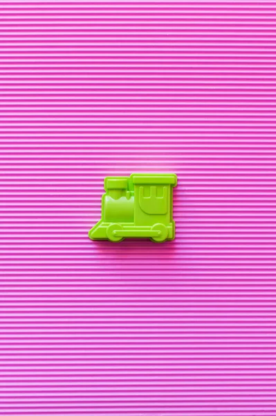 紫罗兰色纹理背景下明亮绿色玩具火车头的顶视图 — 图库照片