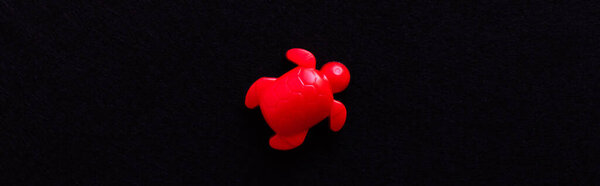 top view of red aquatic turtle toy isolated on black, banner