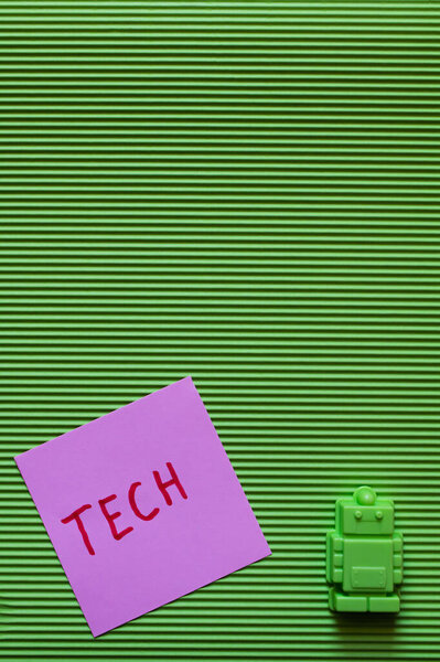 вид на пластиковый игрушечный робот рядом с фиолетовой бумагой с техническими надписями на зеленом текстурированном фоне