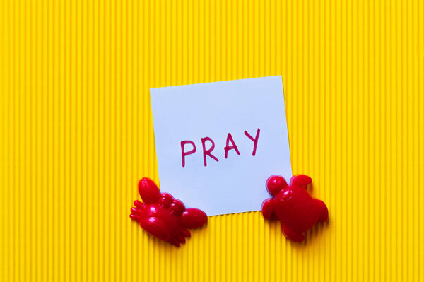 вид карточки с надписью "Молитва" рядом с красным крабом и черепашьими игрушками на желтом фоне