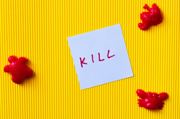 top view of red toy marine animals near blue paper with kill inscription on yellow background