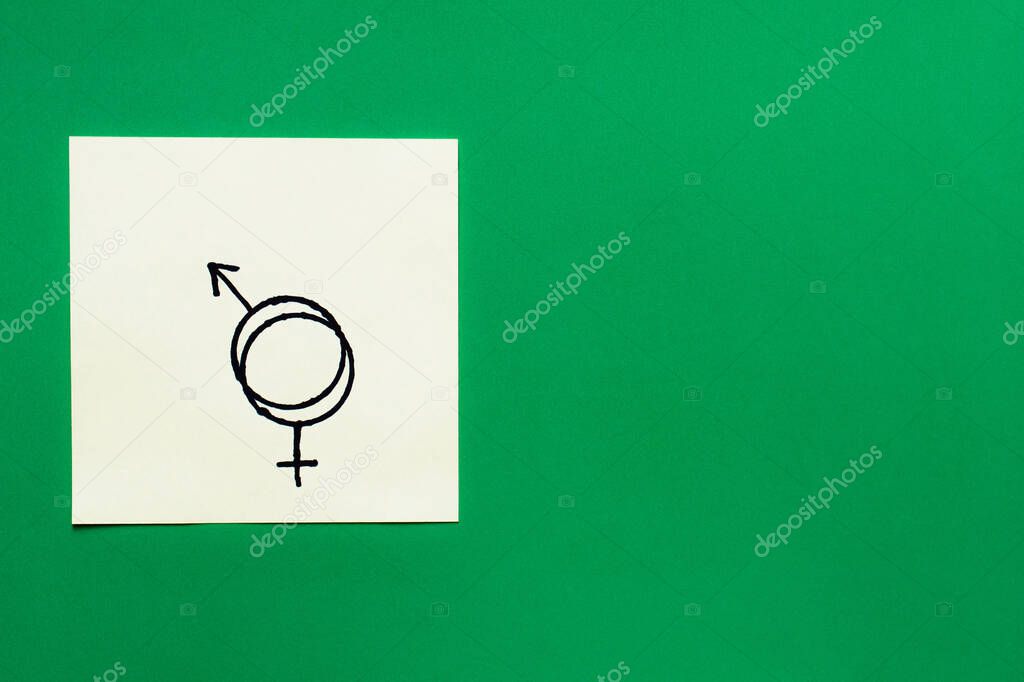 top view of paper card with connected gender identity signs on green background