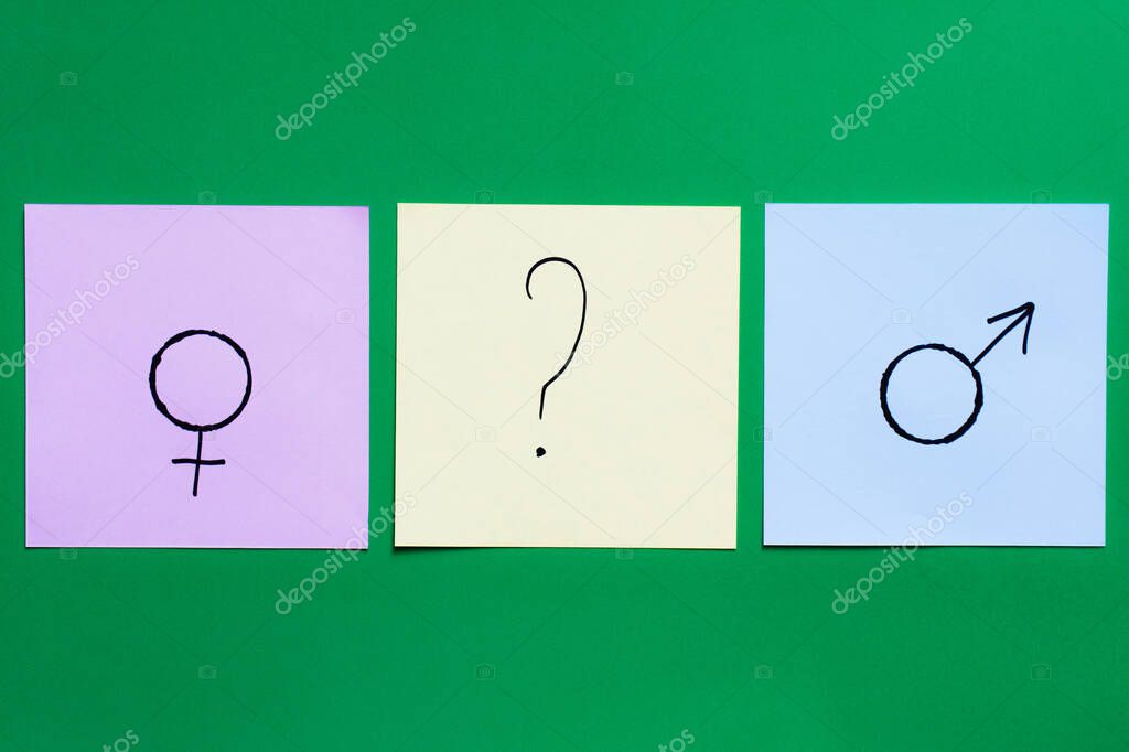 top view of multicolored cards with question mark between gender signs on green background