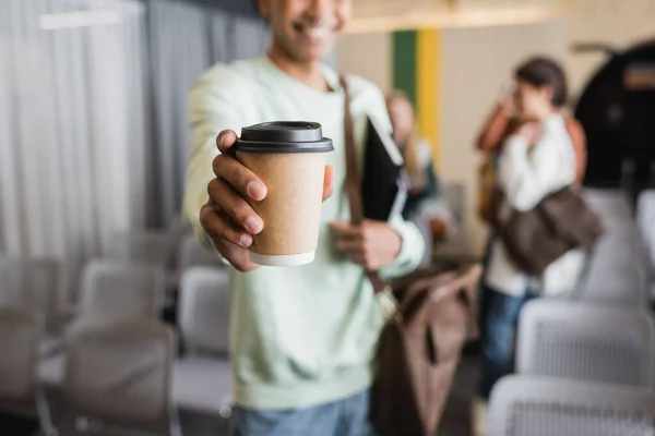 selective focus of disposable cup in hand of african american student on blurred background