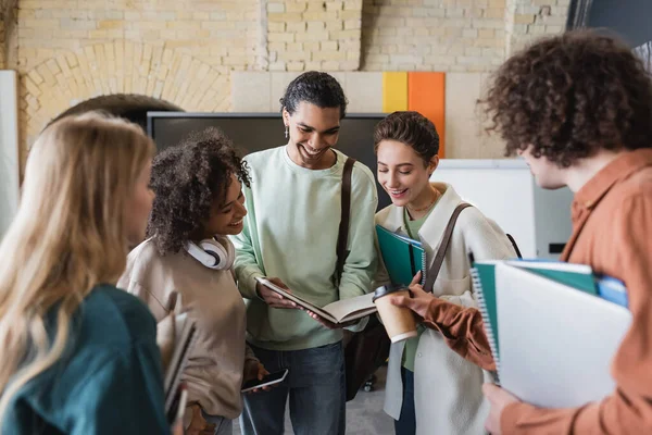 Szczęśliwy African Amerykański Student Pokazując Copybook Wielonarodowych Kolegów — Zdjęcie stockowe