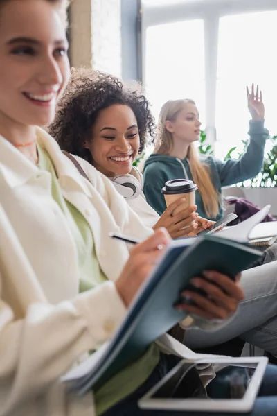 Cheerful African American Woman Holding Coffee Blurred Friend Writing Notebook — Stock Photo, Image