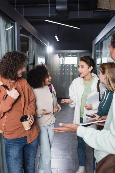 Vidám Interracial Diákok Gesztikulálnak Miközben Beszélnek Egyetem Folyosóján — Stock Fotó