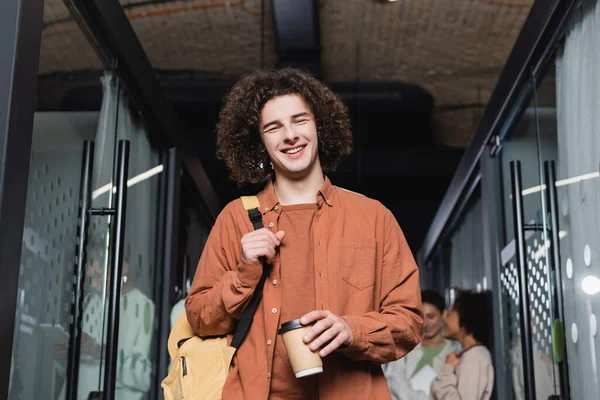 Homem Feliz Encaracolado Com Copo Papel Mochila Sorrindo Para Câmera — Fotografia de Stock