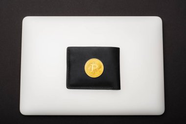 KYIV, UKRAINE - 26 Nisan 2022: Cüzdandaki altın bitcoin ve siyah dizüstü bilgisayarın üst görüntüsü 