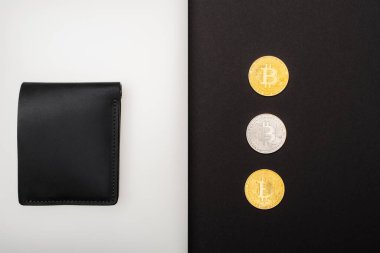 KYIV, UKRAINE - 26 Nisan 2022: Cüzdan yakınındaki bitcoins üst görünümü siyah arkaplan dizüstü bilgisayarı