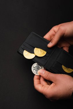 KYIV, UKRAINE - 26 Nisan 2022: Siyah üzerine izole edilmiş gümüş bitcoin ve cüzdan tutan adam görüntüsü 