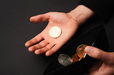 KYIV, UKRAINE - 26 Nisan 2022: Siyah üzerine izole edilmiş altın bitcoin ve cüzdan tutan adam görüntüsü 