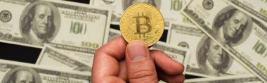 KYIV, UKRAINE - 26 Nisan 2022: Siyah arka plan, pankart üzerinde bulanık para yanında altın bitcoin tutan adamın üst görünümü 