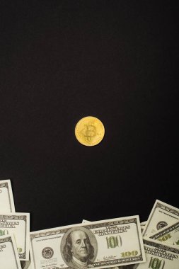 KYIV, UKRAINE - 26 Nisan 2022: Altın Bitcoin ve siyah üzerine izole edilmiş nakit paranın üst görünümü 