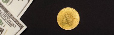 KYIV, UKRAINE - 26 Nisan 2022: Dolar banknotlarının üst görünümü ve siyah, bayrak üzerinde izole edilmiş altın bitcoin