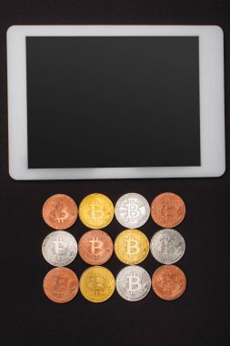 KYIV, UKRAINE - 26 Nisan 2022: Siyah üzerinde izole edilmiş bitcoins yakın boş ekran ile dijital tabletin üst görünümü 