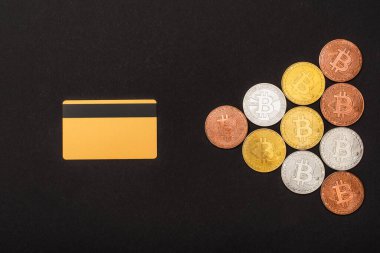 KYIV, UKRAINE - 26 Nisan 2022: Kartın üst görüntüsü ve siyah üzerine izole edilmiş farklı bitcoinler 