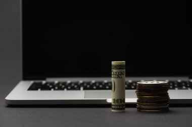 KYIV, UKRAINE - 26 Nisan 2022: Bitcoins yakınlarındaki doların görüntüsünü kapat ve siyah arkaplanda bulanık dizüstü bilgisayar