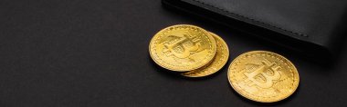KYIV, UKRAINE - 26 Nisan 2022: Siyah arkaplanda cüzdan ve altın bitcoin görüntüsünü kapat, afiş 
