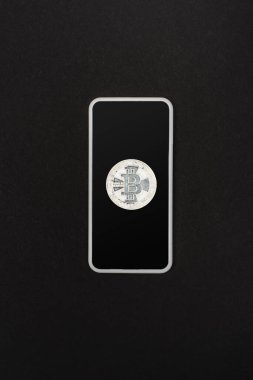 KYIV, UKRAINE - 26 Nisan 2022: Akıllı telefondan izole edilmiş gümüş bitcoin üst görünümü 