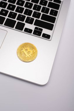 KYIV, UKRAINE - 26 Nisan 2022: Gri arkaplanda dizüstü bilgisayarda altın bitcoin 'in üst görüntüsü 