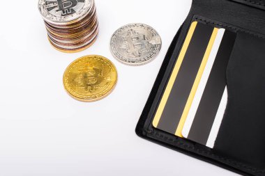 KYIV, UKRAINE - 26 Nisan 2022: Beyaz arka planda kredi kartları ve bitcoins ile cüzdanın üst görünümü 