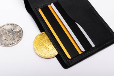 KYIV, UKRAINE - 26 Nisan 2022: Cüzdan yakınındaki bitcoins görüntüsünü beyaz arka planda kredi kartlarıyla kapat 