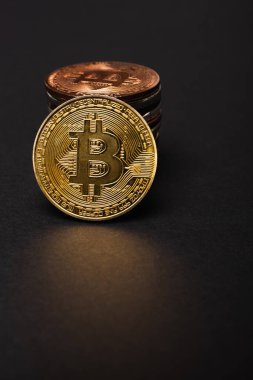 KYIV, UKRAINE - 26 Nisan 2022: Siyah arkaplan üzerindeki kripto para biriminin yanındaki altın bitcoin görünümünü kapat