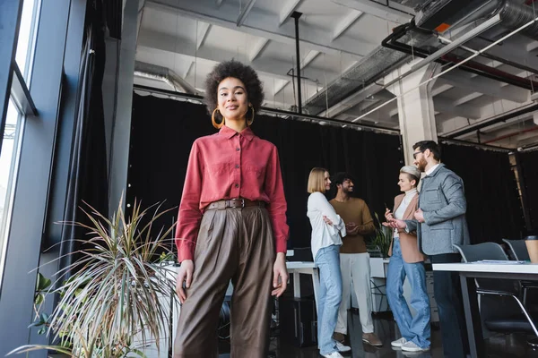 low angle view of smiling african american businesswoman near interracial colleagues talking in ad agency