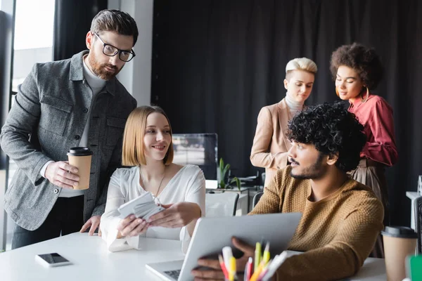 Hombre Con Anteojos Sosteniendo Café Para Acercarse Colegas Interracial Trabajando — Foto de Stock